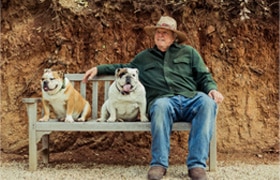 Jerome Gastaldi with bulldogs Artist Jerome Gastaldi sits on a bench outside with two English bulldogs
